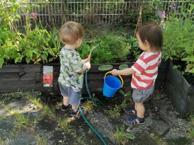 Børn vander planter på legepladsen